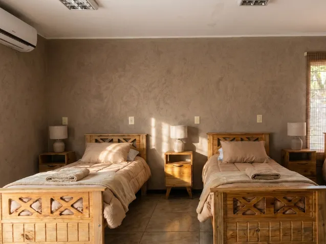 Habitación compartida con camas individuales, mobiliario de madera y luz natural