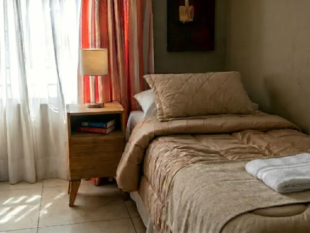 Habitación individual con mesa de luz y luz natural